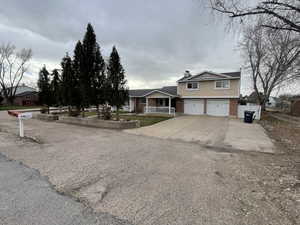 View of front of house featuring a garage, concrete driveway, brick siding, and a chimney