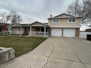 View of front of home featuring covered porch, brick siding, a front lawn, and stucco siding