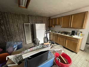 Kitchen with brown cabinets, light floors, light countertops, freestanding refrigerator, and a sink