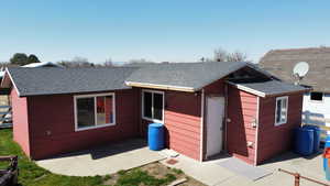 Back of property with a shingled roof and a patio area