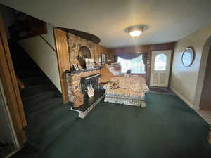 Carpeted bedroom with arched walkways, a fireplace, a textured ceiling, and baseboards