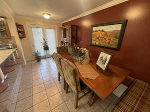 Dining room with crown molding, a textured ceiling, baseboards, and light tile patterned floors