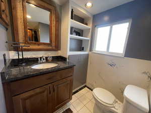 Bathroom with toilet, tile patterned floors, and vanity