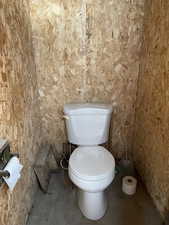 Bathroom featuring unfinished concrete flooring and toilet