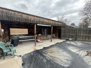 View of patio / terrace with a pole building, an outdoor structure, and fence