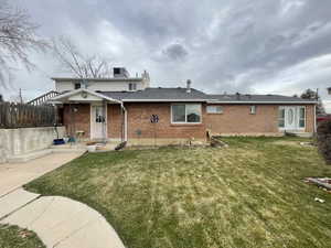 View of front of home with brick siding, a patio, a chimney, a front yard, and fence