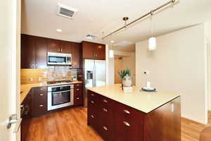 Kitchen featuring light wood-style flooring, stainless steel appliances, and decorative backsplash