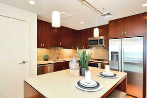 Kitchen with stainless steel appliances,  light countertops, a center island, and tasteful backsplash