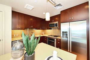 Kitchen with stainless steel appliances, backsplash, light countertops