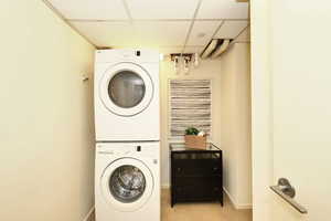 Clothes washing area featuring light tile patterned floors, stacked washer and dryer