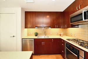 Kitchen with stainless steel appliances, light countertops and backsplash