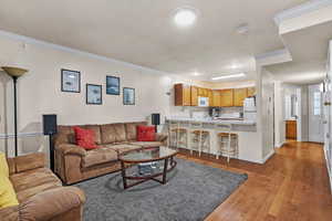 Living area with baseboards, light wood-style floors, a textured ceiling, and crown molding