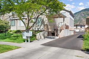 Exterior space featuring stone siding, a mountain view, and a front lawn