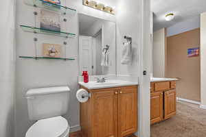 Bathroom with toilet, vanity, and baseboards