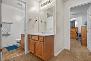 Bathroom featuring baseboards, visible vents, toilet, a textured ceiling, and vanity