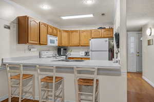 Kitchen featuring white appliances, a sink, a peninsula, and a textured ceiling