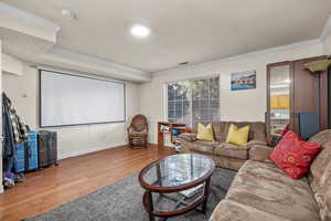 Cinema room featuring visible vents, baseboards, crown molding, and wood finished floors