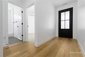 Foyer entrance with baseboards, visible vents, and light wood-style floors