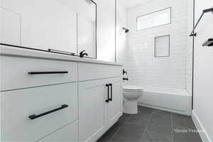 Full bath with bathing tub / shower combination, vanity, toilet, and tile patterned floors