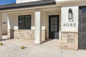 Doorway to property with stone siding and a shingled roof