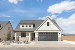 View of front facade featuring concrete driveway, stone siding, and stucco siding