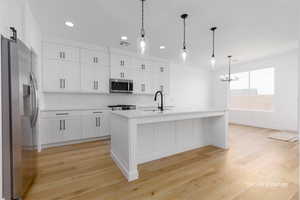 Kitchen featuring visible vents, stainless steel appliances, light countertops, white cabinetry, and a sink