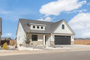 Modern inspired farmhouse with a garage, stone siding, driveway, and board and batten siding