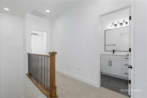 Hall featuring carpet, recessed lighting, visible vents, a sink, and baseboards