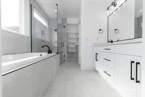 Full bathroom featuring a walk in closet, a garden tub, a stall shower, vanity, and tile patterned floors