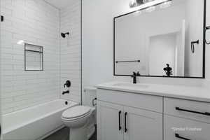 Bathroom featuring tub / shower combination, vanity, and toilet