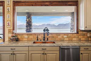 Kitchen featuring a wealth of natural light, dishwasher, backsplash, and a sink