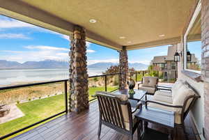 Covered deck with a lawn, an outdoor living space, and water and mountain views