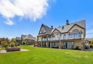 Rear view of house featuring a patio, a lawn, a balcony, and stucco siding