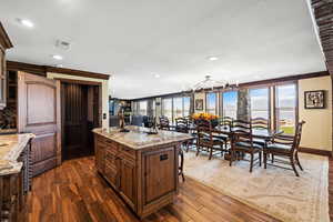 Kitchen featuring dark wood-type flooring, a center island, a kitchen breakfast bar, and an inviting chandelier