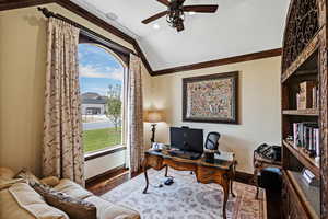 Home office with ornamental molding, lofted ceiling, baseboards, and wood finished floors