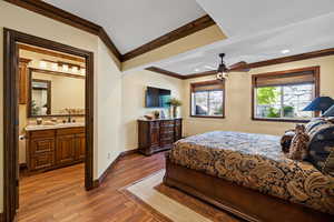 Bedroom with baseboards, connected bathroom, ornamental molding, and wood finished floors