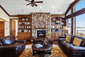 Living room with recessed lighting, ornamental molding, a ceiling fan, a stone fireplace, and wood finished floors