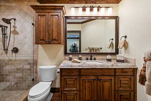 Full bath featuring tiled shower, crown molding, vanity, and toilet