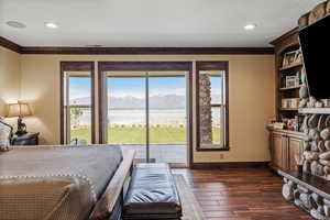 Bedroom featuring access to exterior, wood finish floors, ornamental molding, and baseboards