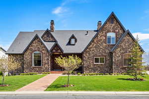 English style home featuring a front yard, roof with shingles, and a chimney