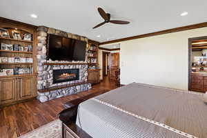 Bedroom with ornamental molding, dark wood-style flooring, a fireplace, and recessed lighting