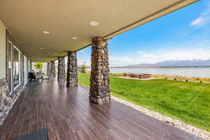 Covered deck with a yard and a water and mountain view