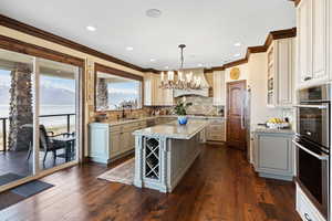 Kitchen with a kitchen island, a sink, appliances with stainless steel finishes, dark wood-style floors, and custom range hood