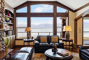 Living room with lofted ceiling, a healthy amount of sunlight, baseboards, and dark wood-style flooring