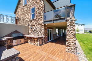 Rear view of property with a patio, an outdoor kitchen, a balcony, a yard, and stucco siding