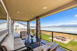 View of patio featuring a balcony, a water and mountain view, and an outdoor living space with a fire pit