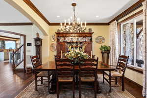 Dining room featuring arched walkways, dark wood finished floors, crown molding, and baseboards