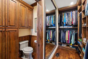 Bathroom featuring a wainscoted wall, visible vents, toilet, and wood finished floors