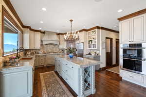 Kitchen featuring dark wood finished floors, open shelves, custom range hood, appliances with stainless steel finishes, and a sink