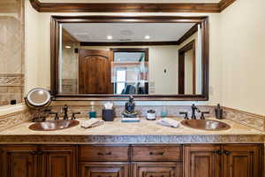 Bathroom featuring double vanity, ornamental molding, and a sink